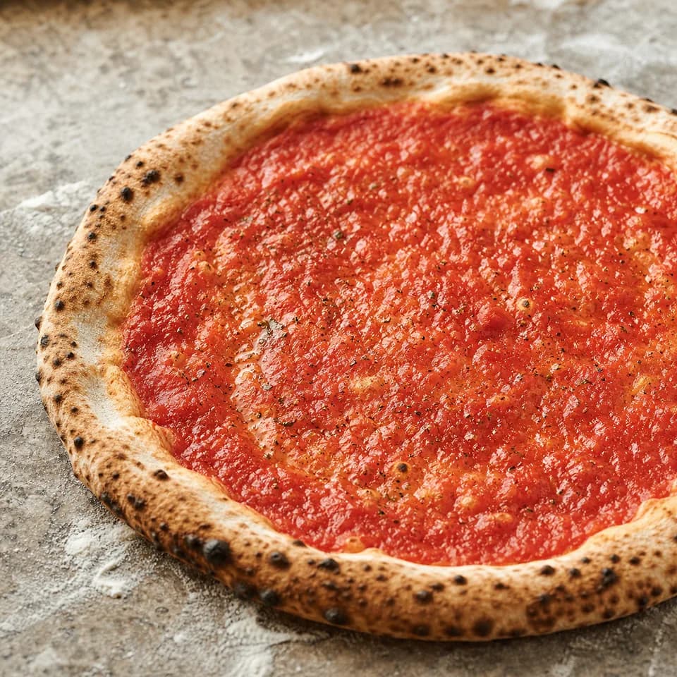 Pizza base with a thin even tomato sauce layer and a clean crust border